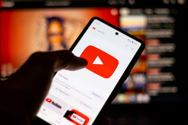 Fotografía realista de un creador digital en su estudio usando herramientas de YouTube con pantallas modernas y elementos de inteligencia artificial.