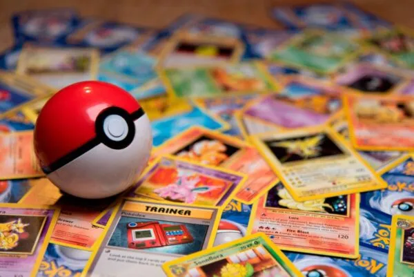 Cartas Pokémon junto a una caja Happy Meal sobre una mesa, con luz cálida y fondo neutro, imagen horizontal editorial