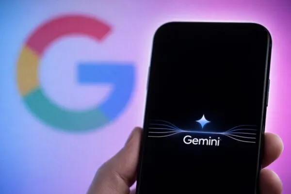 Primer plano de un smartphone con la app Gemini abierta y el logo de Google al fondo desenfocado