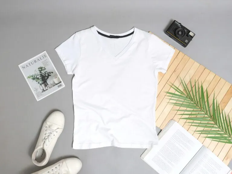 Persona diseñando camisetas personalizadas con software gráfico en laptop, entorno moderno y creativo