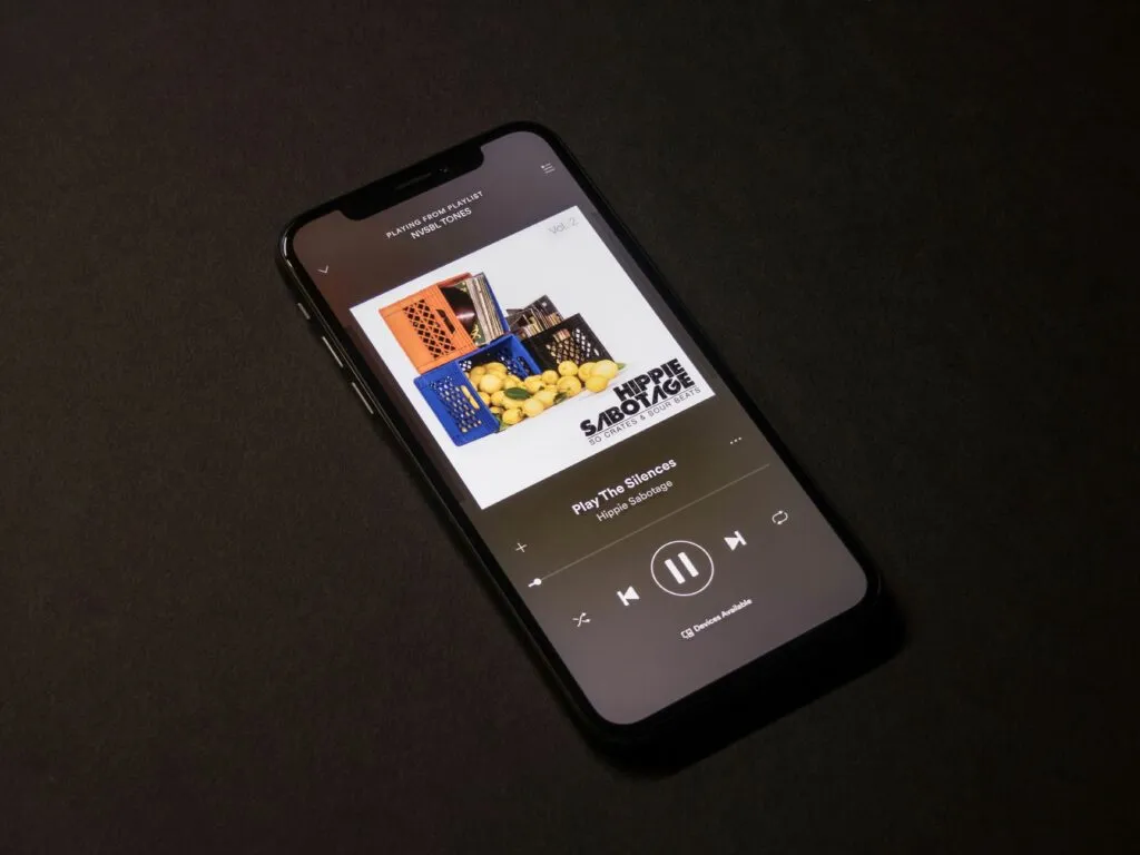 Persona joven utilizando app de reconocimiento musical en su celular con interfaz de Shazam visible