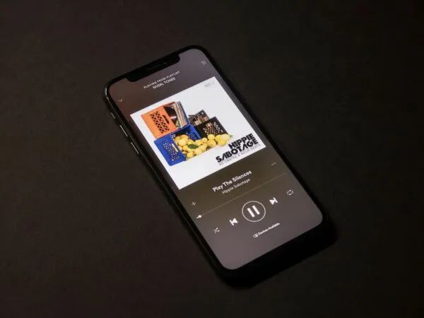 Persona joven utilizando app de reconocimiento musical en su celular con interfaz de Shazam visible