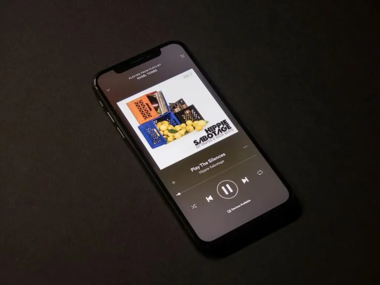 Persona joven utilizando app de reconocimiento musical en su celular con interfaz de Shazam visible