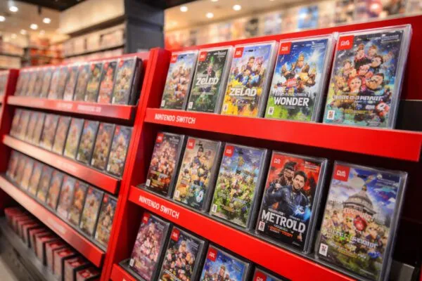 Cajas de juegos físicos de Nintendo Switch y Switch 2 en estantes de tienda frente a clientes comprando