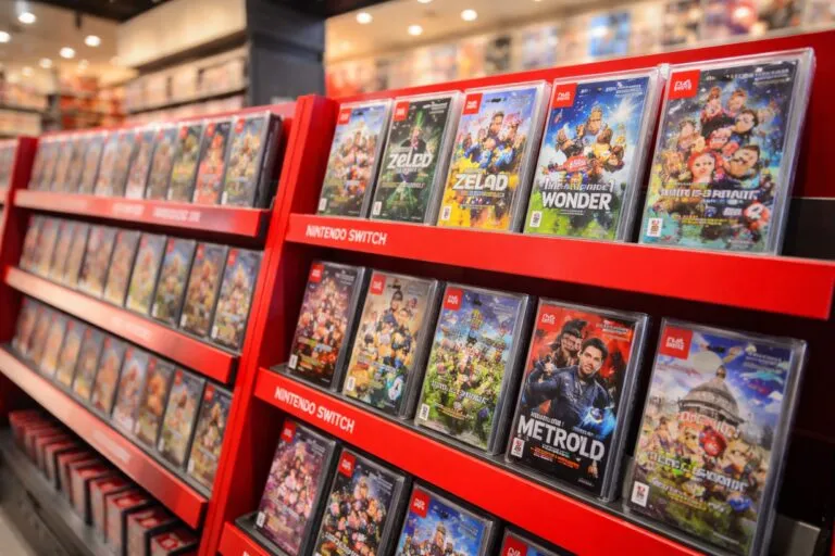 Cajas de juegos físicos de Nintendo Switch y Switch 2 en estantes de tienda frente a clientes comprando