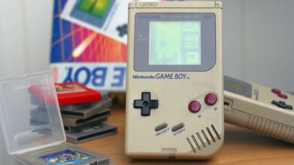 Game Boy clásico mostrando videojuegos portátiles en un entorno retro inspirado en la cultura gamer