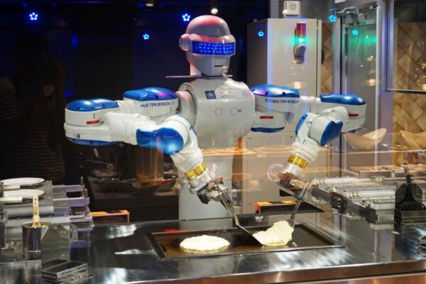 Robot chef preparando alimentos en una cocina profesional equipada con inteligencia artificial y tecnología avanzada