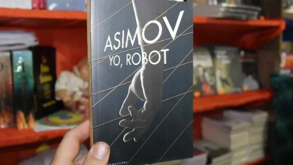 Libro Yo, robot junto a un robot humanoide moderno representando la evolución de la inteligencia artificial.