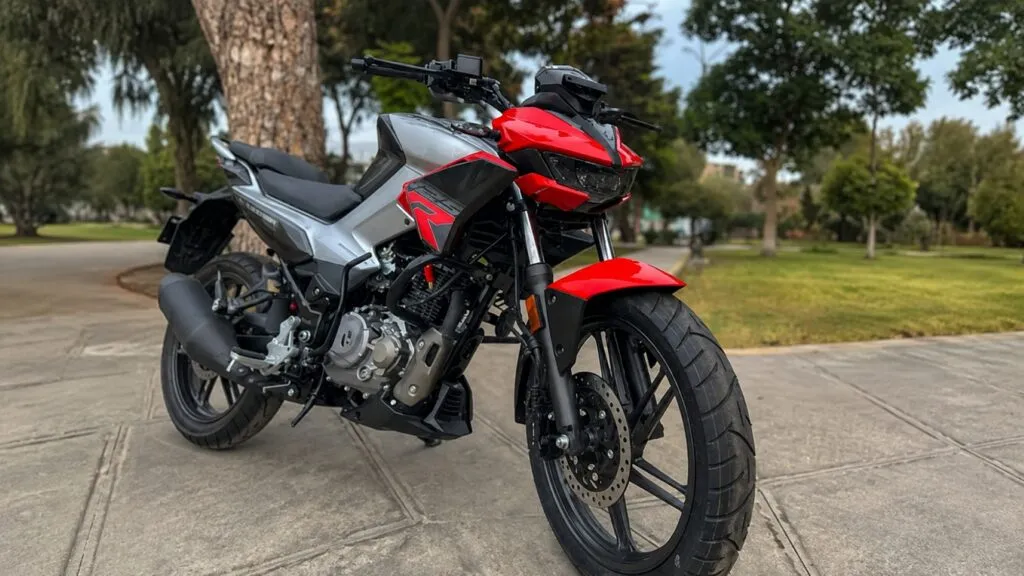 Hero Hunk 125R negra con detalles rojos en un entorno abierto de Mendoza, Argentina, acompañada por un paisaje urbano y montañoso.