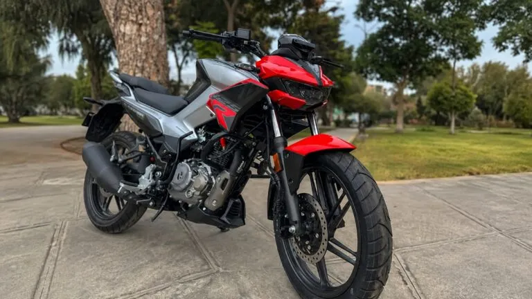 Hero Hunk 125R negra con detalles rojos en un entorno abierto de Mendoza, Argentina, acompañada por un paisaje urbano y montañoso.
