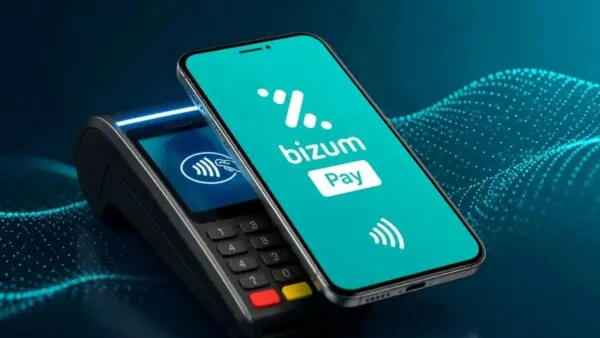 Celular acercándose a un terminal de pago para representar las compras presenciales mediante Bizum Pay.