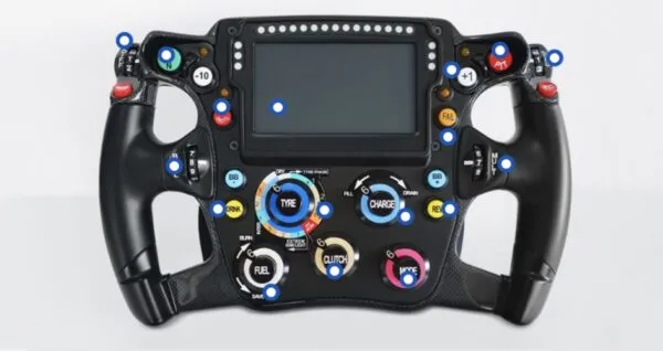 Volante de Fórmula 1 con pantalla digital, botones, perillas y paletas para controlar diferentes funciones del monoplaza.