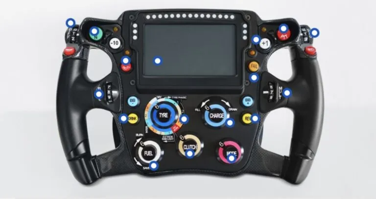 Volante de Fórmula 1 con pantalla digital, botones, perillas y paletas para controlar diferentes funciones del monoplaza.